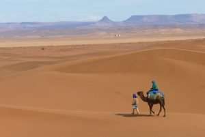 Barbara-Mira sitzt auf dem Kamel und reitet durch die Weite der Wüste