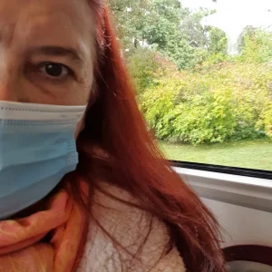 Frau mit Mund- und Nasenschutz in Bus sitzend